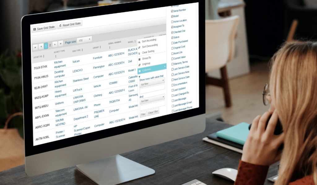 A woman sits in front of a monitor displaying a digital asset database