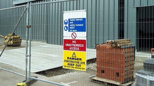 Construction site safety sign behind a fence
