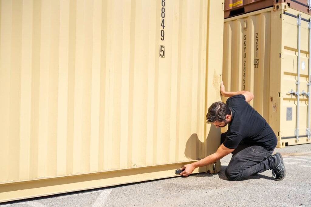 Person attaching a GPS tracker to a cargo container