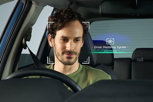 Man driving a car while an AI-powered Driver Monitoring System scans his face and head position