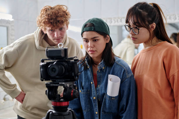 istockphoto-2167307398-612x612 1 Group of young adults collaborating on creative project in indoor setting, involving filming process with professional camera equipment